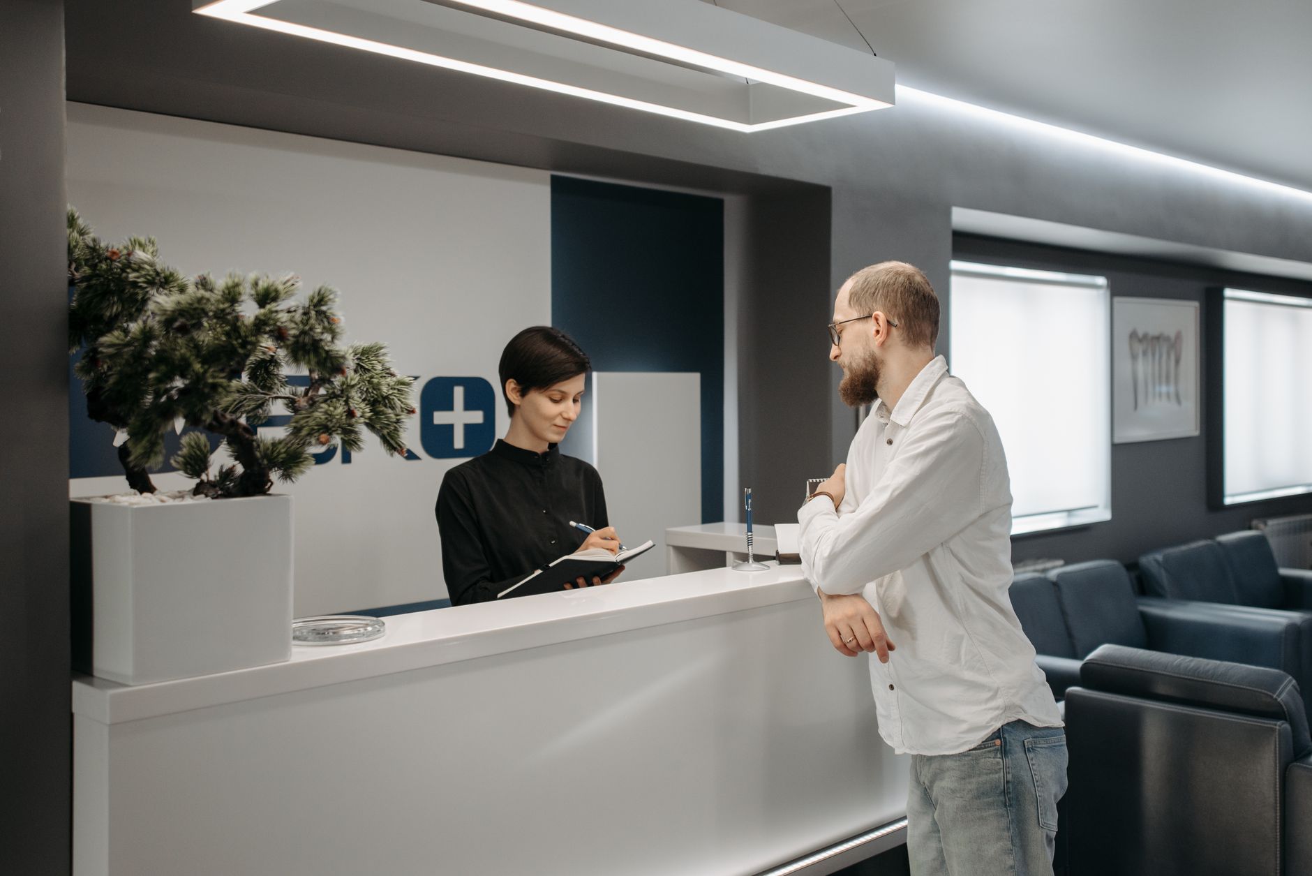 Recepção de escritório com atendente e cliente no balcão